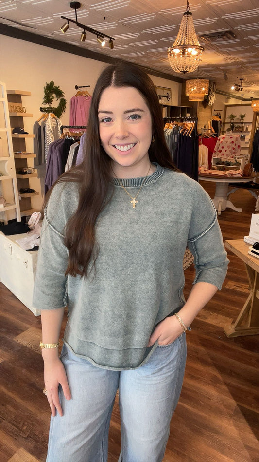 Woman wearing a jade sweater and blue jeans in a store setting